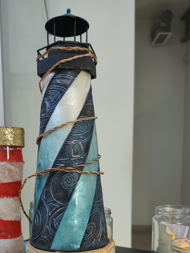 Dois faróis feitos pelos alunos, um em metal e outro em papel, junto a frascos com pequenas luzes
