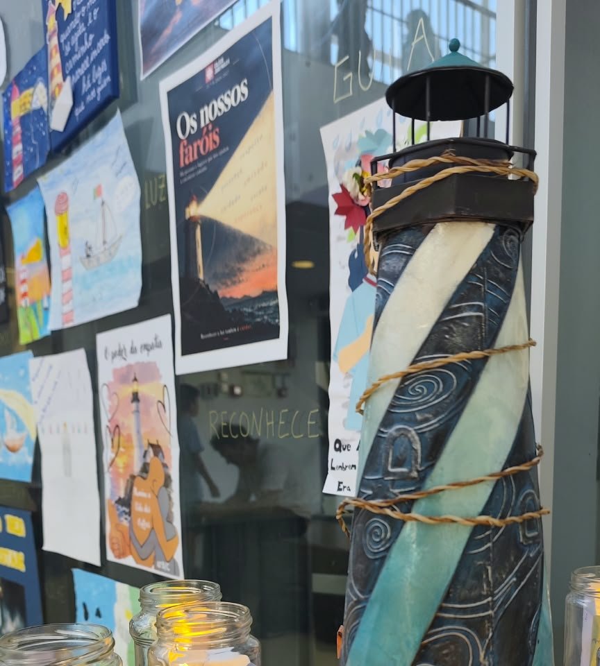 Um farol de metal e cartazes sobre faróis, expostos junto a frascos com pequenas luzes